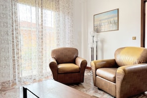 Um quarto com duas poltronas de couro, um abajur e um quadro na parede.