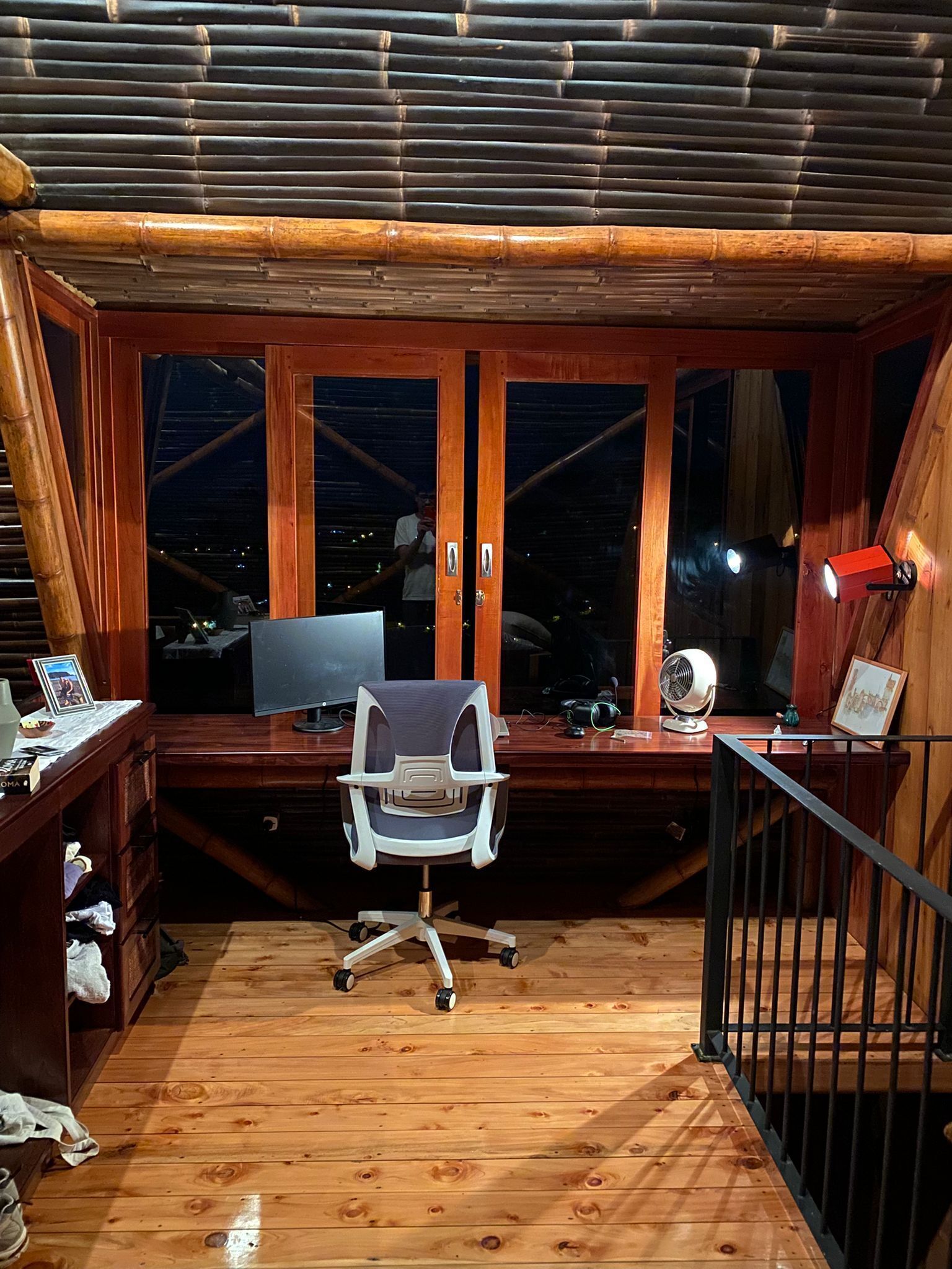 Een houten terras met een bureau, stoel en computer.