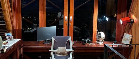 Une terrasse en bois avec un bureau, une chaise et un ordinateur.
