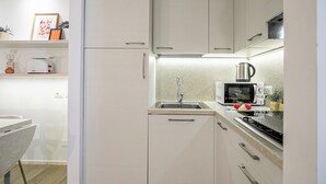 Cocina compacta con microondas, lavabo y estufa.