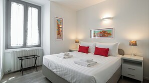 A hotel room with a large bed, two bedside tables, a radiator, and two wall-mounted lamps. - Italianway Comfort - Bligny 19 E (Milan)