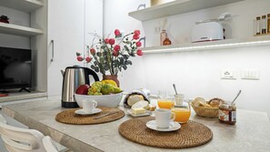 A breakfast setup with a coffee maker, a bowl of fruit, and a glass of orange juice on a kitchen counter. - Italianway Comfort - Bligny 19 E (Milan)