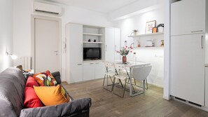 A compact living space with a sofa, a dining table with chairs, a TV, and a kitchenette with a refrigerator. - Italianway Comfort - Bligny 19 E (Milan)