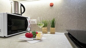 A kitchen counter with a microwave, a glass of white wine, fresh vegetables, and two potted plants. - Italianway Comfort - Bligny 19 E (Milan)