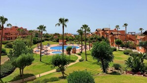 Ein Resort mit Swimmingpool, Palmen und Gebäuden mit roten Dächern.