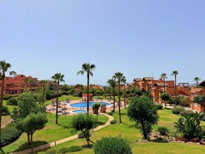 Ein Resort mit Swimmingpool, Palmen und Gebäuden mit roten Dächern.