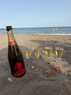 A bottle of champagne and four glasses on a sandy beach with the ocean in the background. - Your peaceful retreat... Mi Casa del Sol in Casarès, with a pool just 1.3 km from the sea! (Casares)