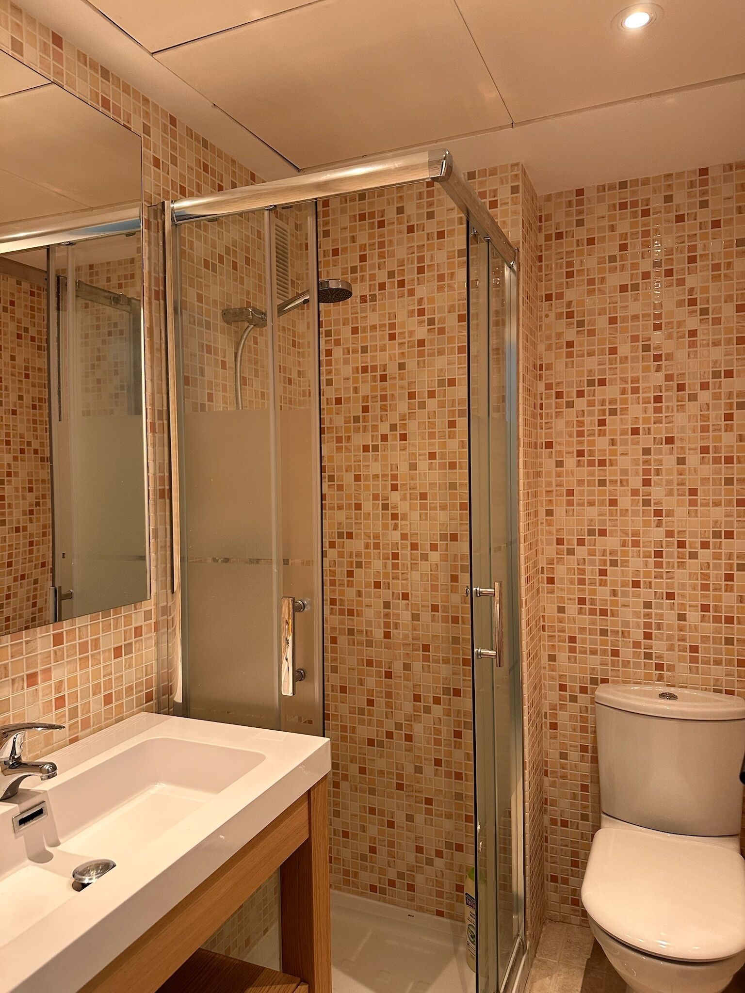 Een badkamer met een glazen douchecabine, een wit wastafelmeubel en een toilet.