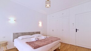 Ein Schlafzimmer mit Bett, Nachttischen, einem Kleiderschrank und einer Pendelleuchte.