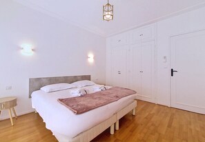 Quarto com cama, mesas de cabeceira, guarda-roupa e luminária suspensa.
