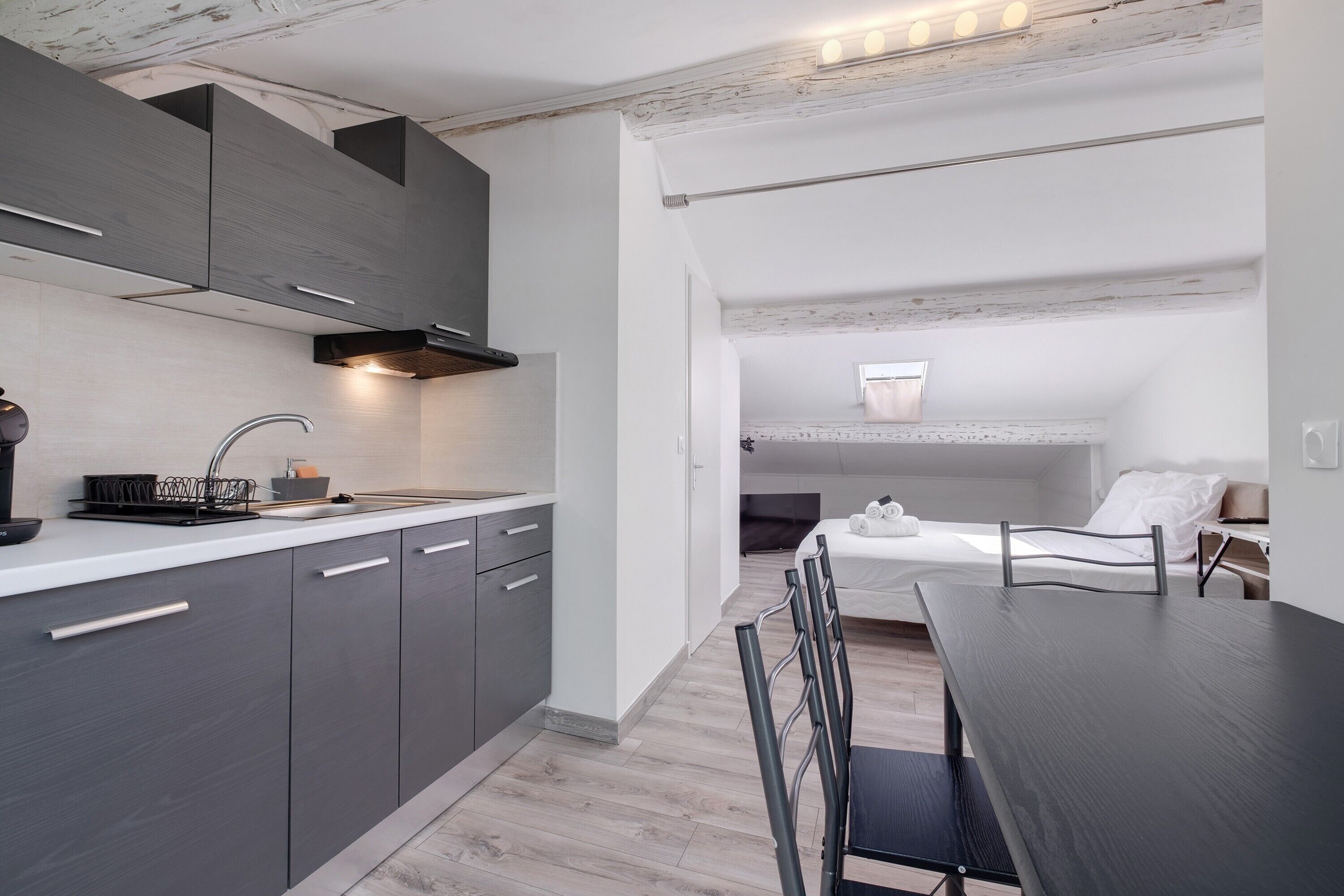 A modern kitchen with grey cabinets, a black range hood, and a white countertop.