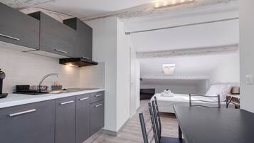 A modern kitchen with grey cabinets, a black range hood, and a white countertop.