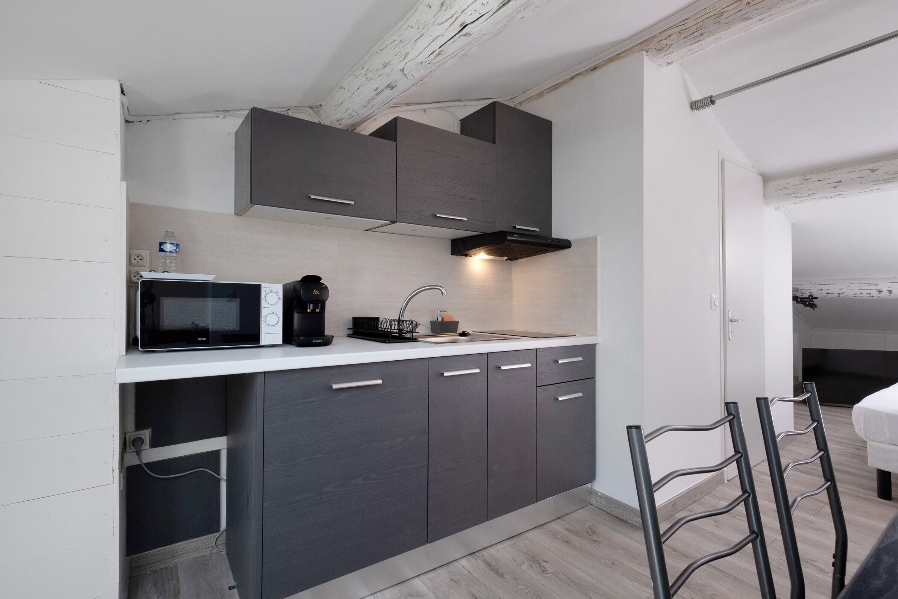 Una cocina compacta con electrodomésticos modernos, microondas integrado y un lavabo.