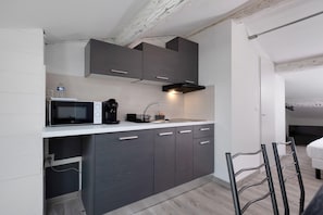 Ett kompakt kök med moderna vitvaror, en inbyggd mikrovågsugn och en diskho.