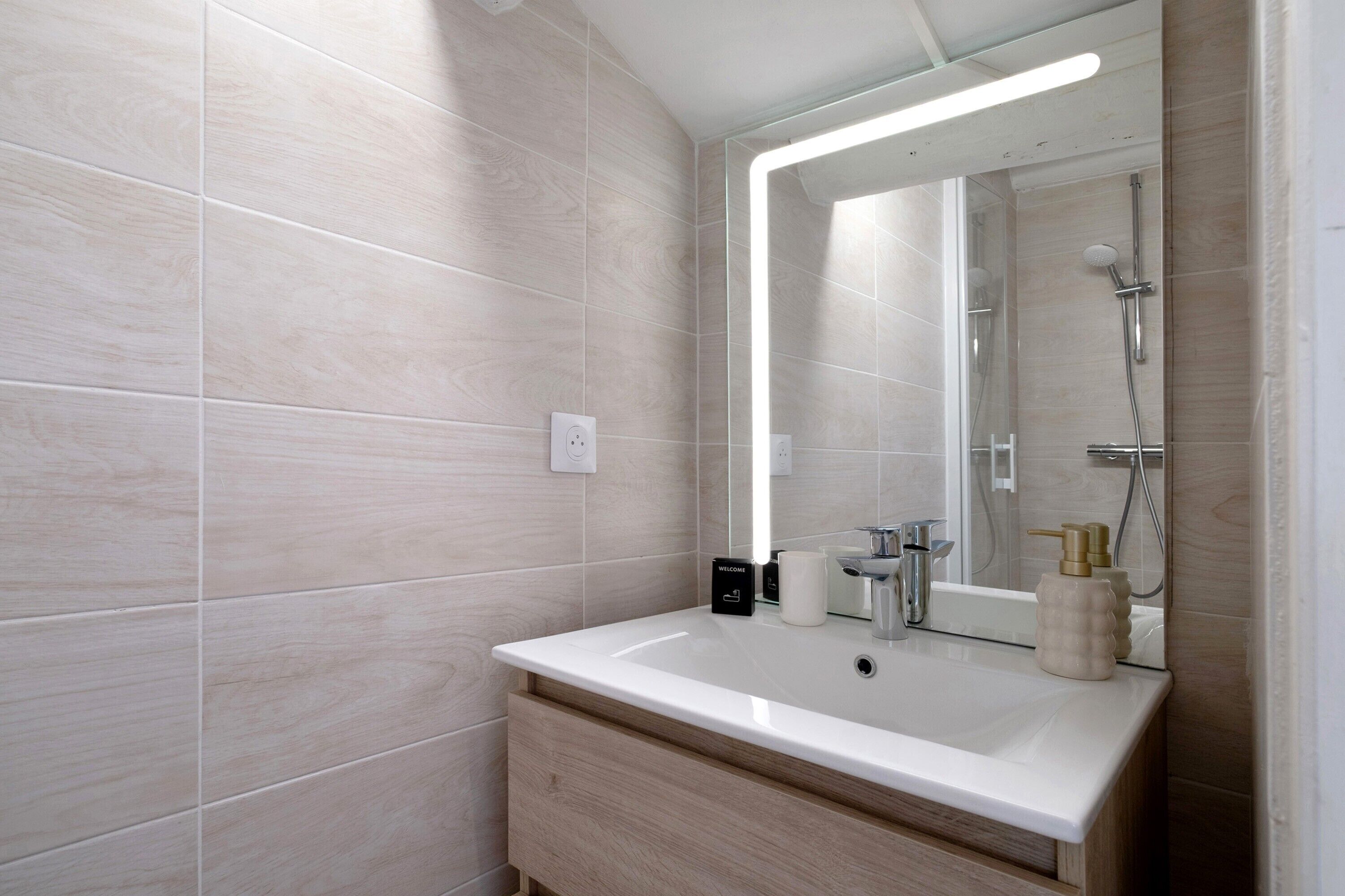 A bathroom with a large mirror, a sink, and a shower.