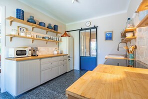 Uma cozinha moderna com prateleiras de madeira, uma geladeira, uma cafeteira e um relógio na parede.