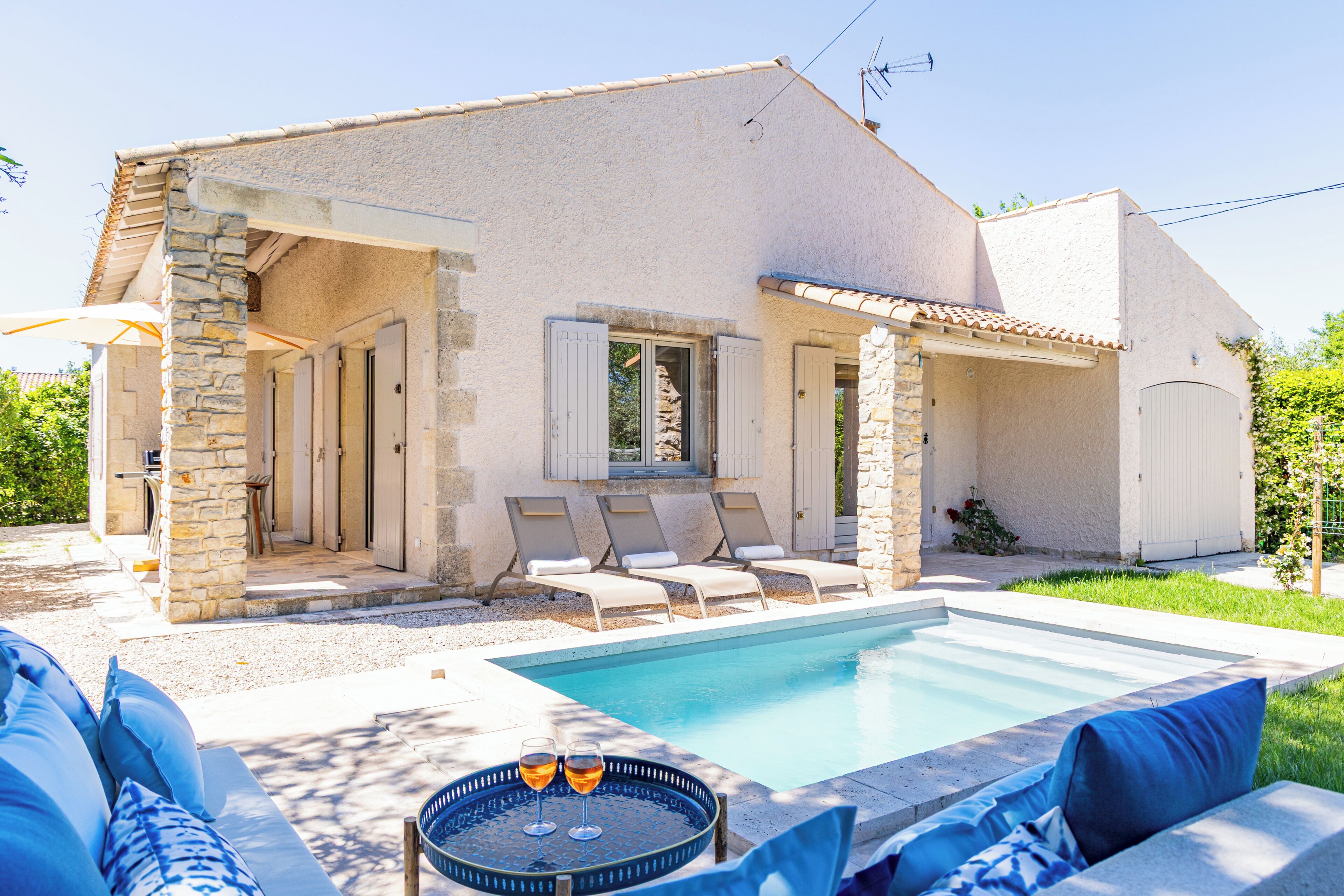 Un espace aménagé au bord de la piscine, comprenant une piscine, des chaises longues et une table avec des verres.