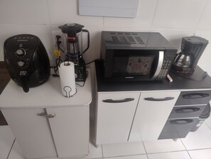 Pieni keittiönurkkaus, jossa on kahvinkeitin, mikroaaltouuni, tehosekoitin ja paperipyyhen annostelija.