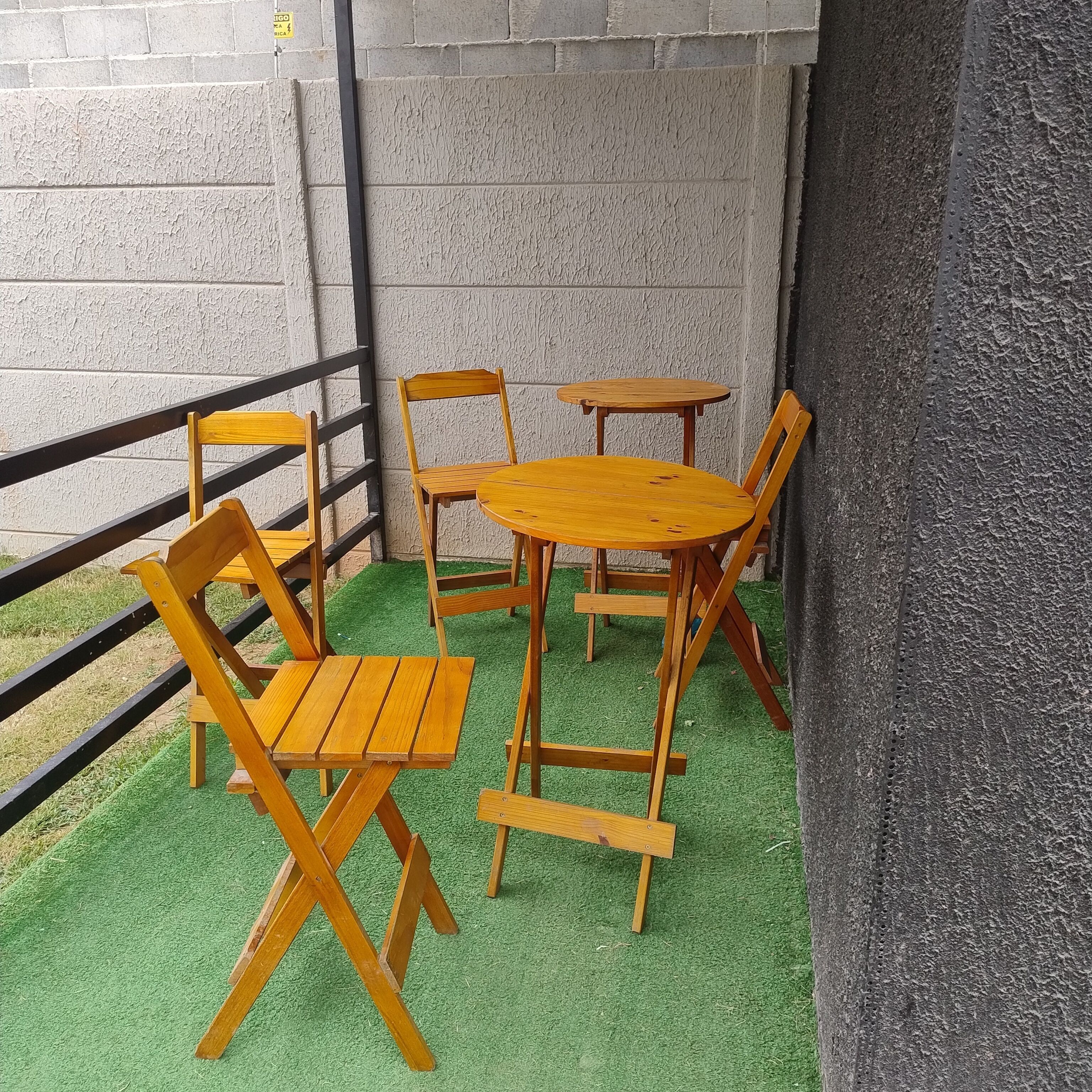 A patio area with a wooden table and chairs, a metal railing, and a textured wall.