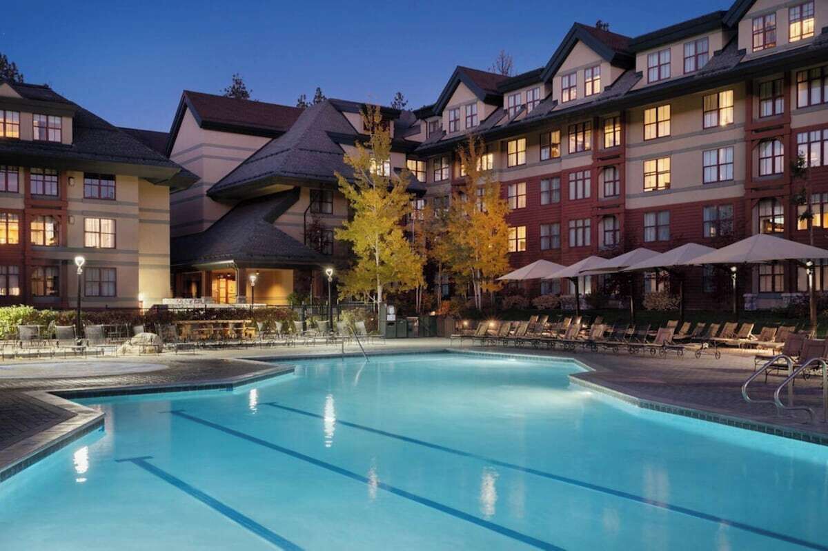 A hotel with a swimming pool, outdoor seating, and a covered area.