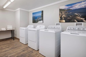 A laundry room with three stacked front-loading washers and dryers, a wooden floor, and two wall-mounted pictures. - 2 Bedroom Villa Timber Lodge Resort S Lake Tahoe (South Lake Tahoe)