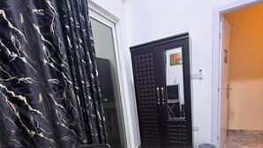 A room with a bed, a chair, a wardrobe, and a door leading to another room. - Four Stars Residence (Dubai)