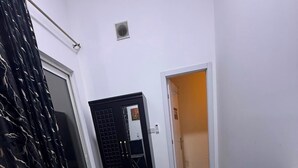 A bedroom with a bed, a chair, a door, and a small window. - Four Stars Residence (Dubai)