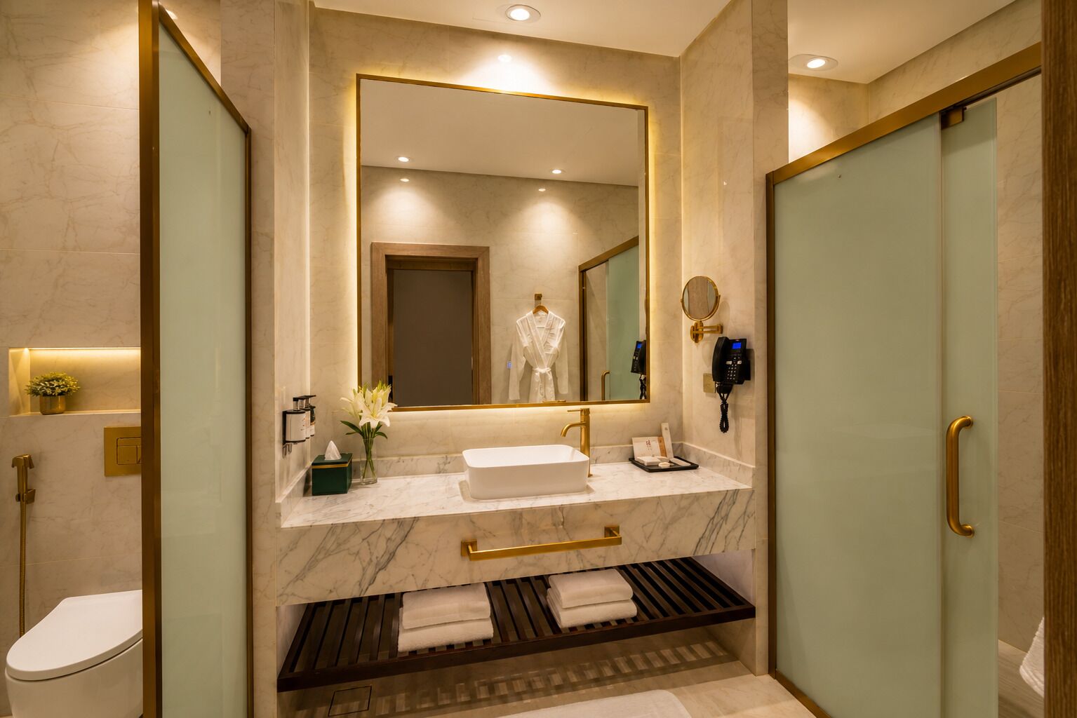 Ein modernes Badezimmer mit großem Spiegel, Waschbecken in Weiß, Handbrause und Toilette.