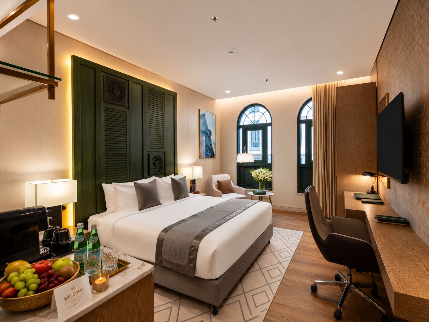 A hotel room with a large bed, a desk, a chair, a TV, and a window with curtains.