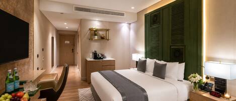 Habitación de hotel con cama, mesita de noche, televisor, escritorio y frutero.