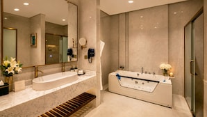 A modern bathroom with a large mirror, two sinks, a bathtub, and a shower.