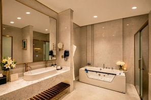 A modern bathroom with a large mirror, two sinks, a bathtub, and a shower.