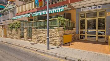 Un edificio con fachada de piedra, una entrada porticada y un cartel que dice 'Edifici ALASIO 64'.