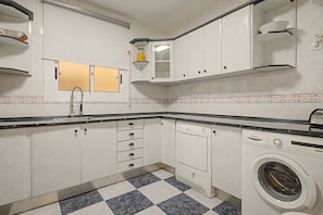 A compact kitchen with a built-in dishwasher, a washing machine, and a tiled backsplash. - Apartment 'Sunandbed Sol' with Private Terrace, Balcony and Air Conditioning (Salou)
