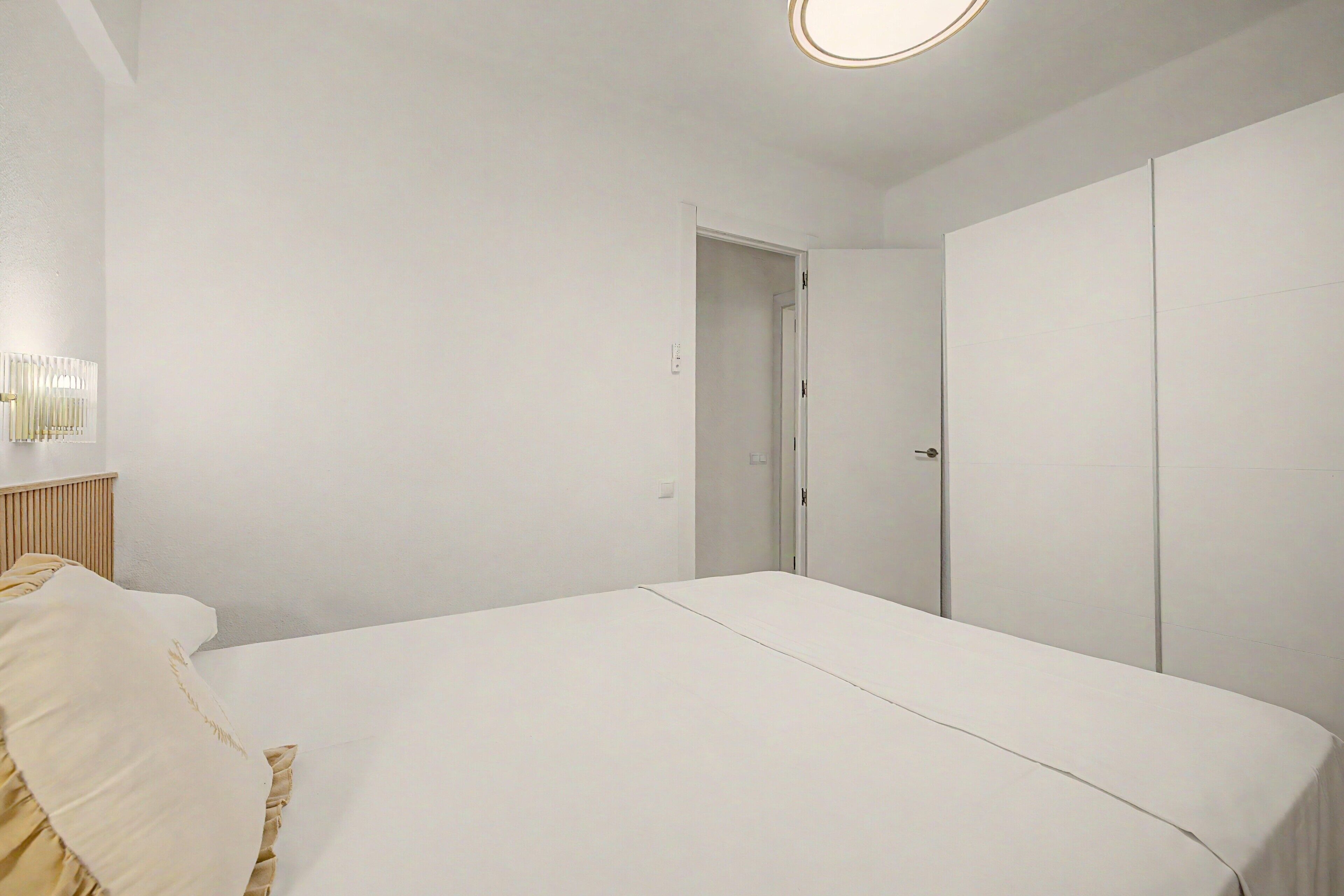 Un dormitorio con cama, armario y puerta que da a otra habitación.