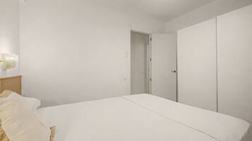 Un dormitorio con cama, armario y puerta que da a otra habitación.