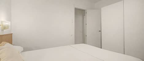 Un dormitorio con cama, armario y puerta que da a otra habitación.