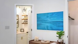 Ein Badezimmer mit einem großen blauen Gemälde, einem hölzernen Waschtisch und einer Topfpflanze.