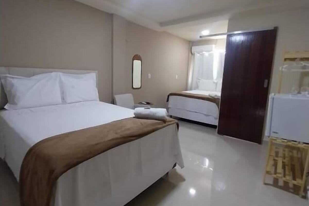 Une chambre d’hôtel comprenant un lit, une table de chevet, un miroir, une armoire et une salle de bain avec douche.