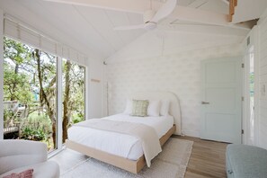 Um quarto com uma cama, um ventilador de teto e vista para o exterior.