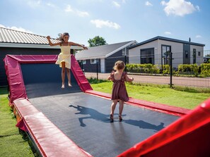 Ein Trampolin in einem Garten, im Hintergrund ein Haus.
