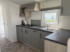 Eine moderne Küche mit grauen Schränken, einer Edelstahlspüle und einem Fenster mit Blick auf ein Haus.