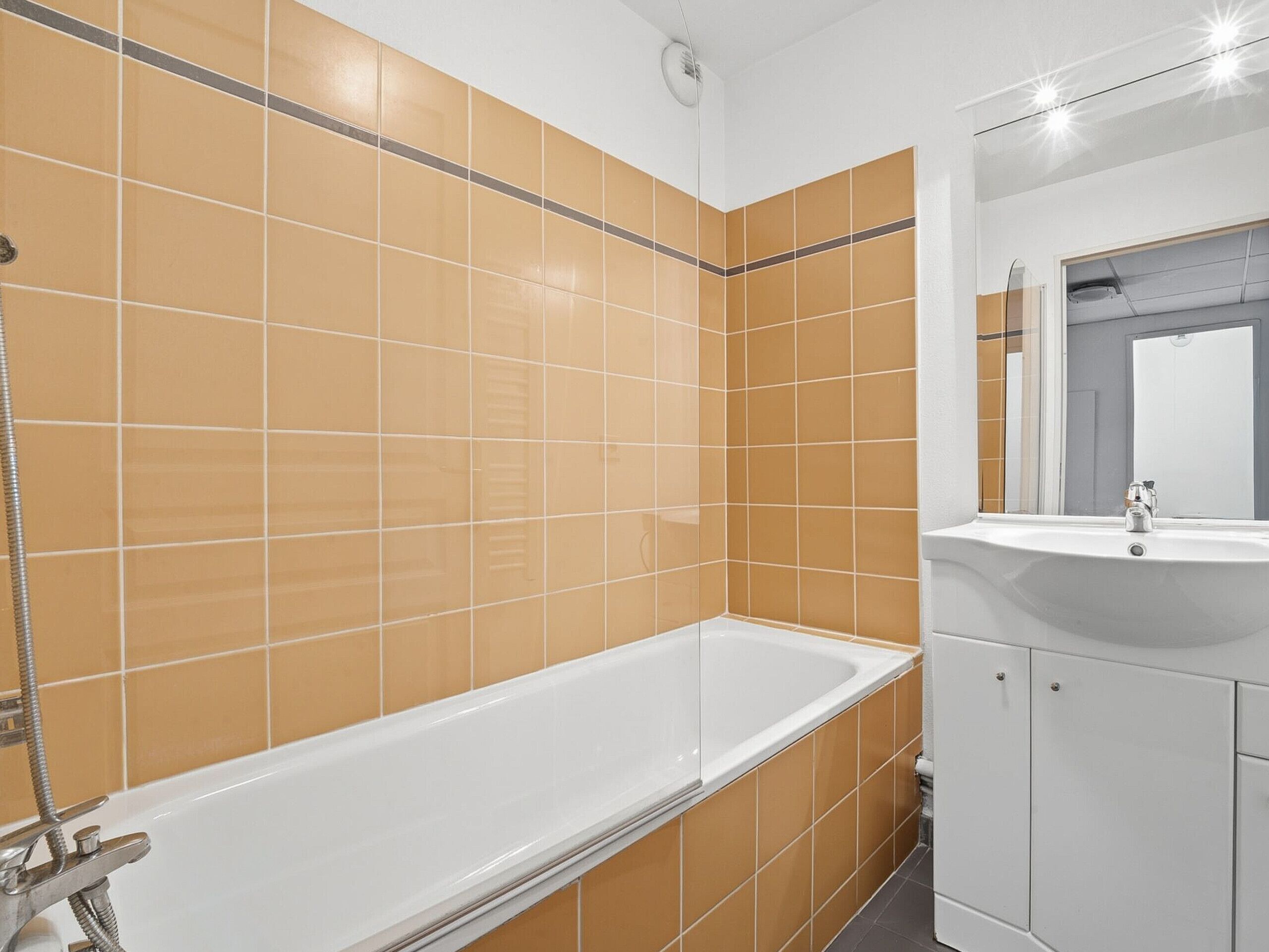 Een badkamer met een bad, een wastafel en een spiegel.