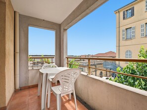 Ein Balkon mit Tisch und Stühlen, Blick auf Gebäude und einer Brüstung.