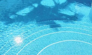 A clear view of a swimming pool with visible water patterns and a tiled edge.