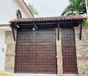 A building with a stone facade, a tiled roof, and two large metal gates.