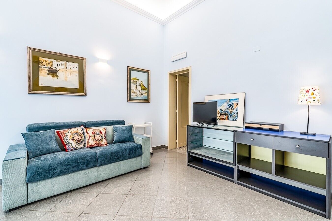 A modern living room with a blue sofa, a flat-screen TV, and a cabinet with drawers.
