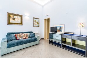 Ein modernes Wohnzimmer mit einem blauen Sofa, einem Flachbildfernseher und einer Kommode mit Schubladen.