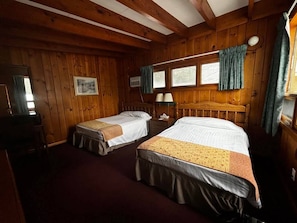 A cabin-style room with two beds, wooden walls, a window with curtains, a desk, and a chair. - Cozy 1BR hotel room, Hamilton - #338 Huron (Hamilton)