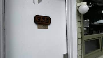Uma porta branca com placa de identificação e aviso de proibido fumar.